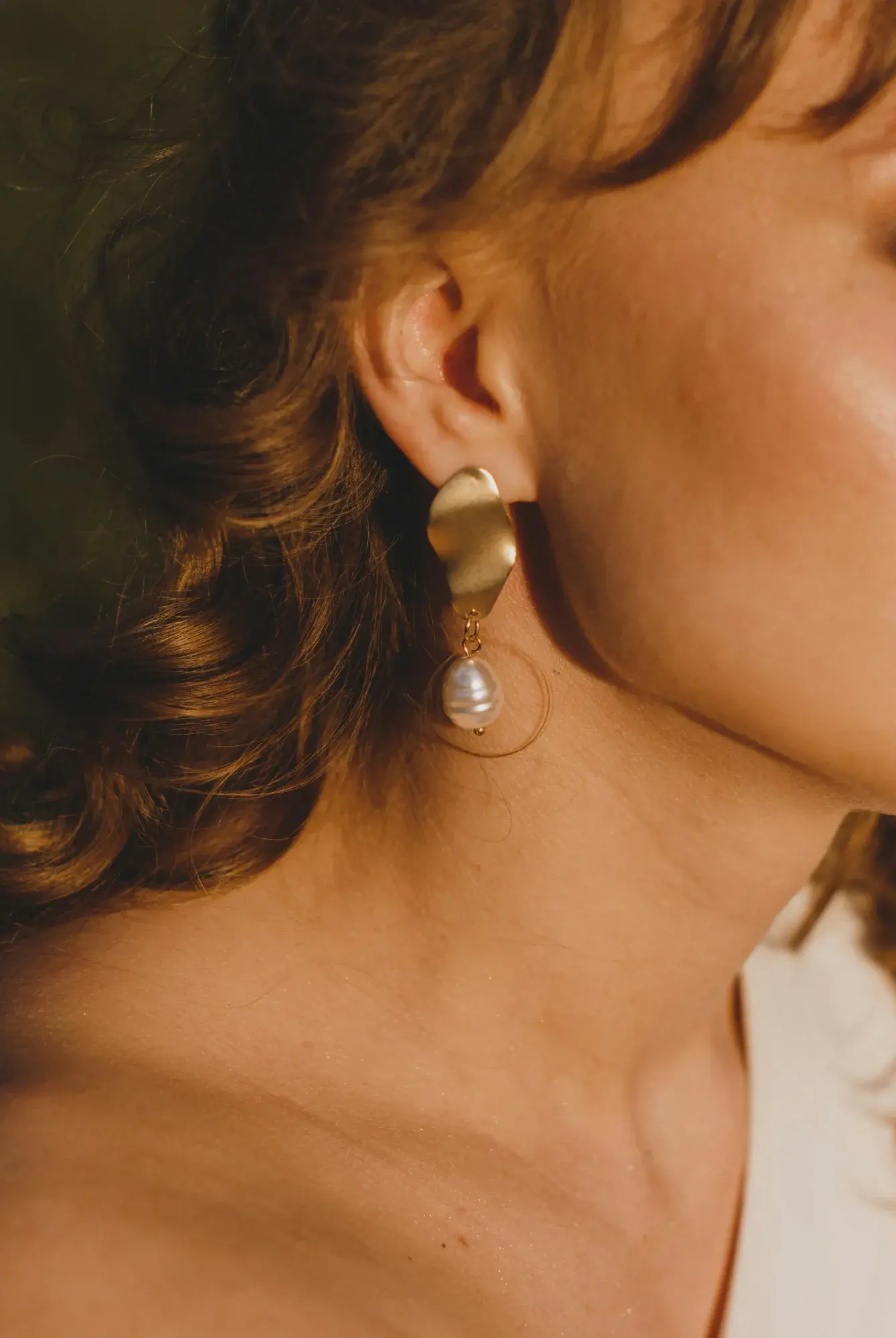 Modelo con pendientes de nácar y oro a la luz del sol